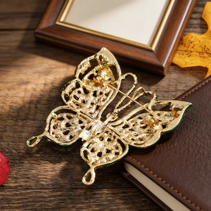 Broche papillon vintage ajourée dorée avec émail vert sur un carnet de cuir