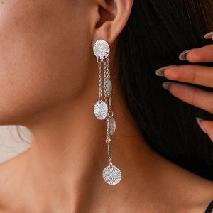 Close-up of silver long tassel earrings with layered round metallic texture on model