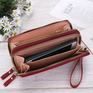 Detail of red dual-zipper leather wallet showing interior card slots and phone pocket