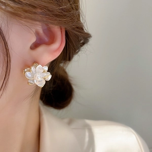 Macro detail of French flower earring with pearl center and golden finish petals