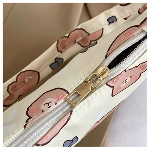Close-up of beige fabric shoulder bag featuring cute cartoon bear print and gold zipper