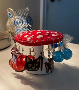 Detail view of red mushroom earring stand with multiple holes for jewelry display