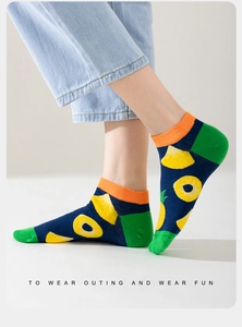 Detail of low-cut cotton sock featuring pineapple pattern and vibrant orange ribbed cuff
