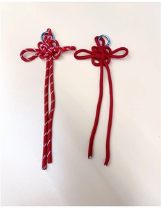 Close-up of handmade Chinese knot charms in solid red and red-white braided patterns