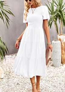Detailed view of white tiered dress with smocked bodice and layered ruffle hemline