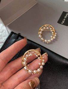 Macro detail of 24k gold-plated round brooch with white pearls and sparkling zircons