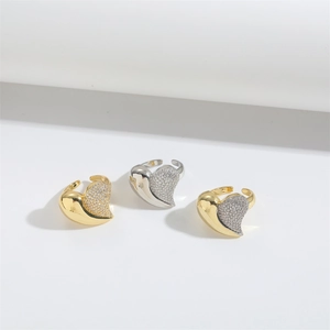 Macro detail of asymmetric heart rings with gold and silver finishes and zircon pavé