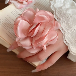 Detail eines rosa Satin-Blumenrings, gehalten von einem Modell vor elegantem Vintage-Hintergrund