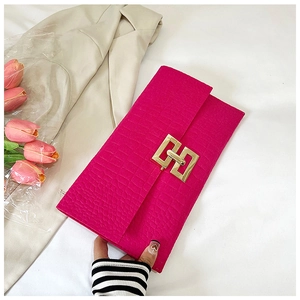 Detail of rose red crocodile embossed clutch bag with golden geometric twist lock closure