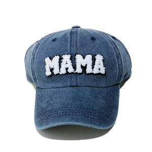 Close-up of white MAMA towel embroidery on a washed navy denim baseball cap detail