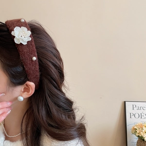 Detailed view of coffee-colored wide headband with white 3D flower and elegant pearls