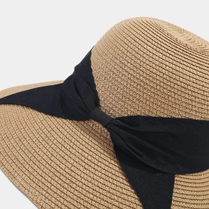 Straw sun hat with a wide brim and black ribbon bow detail, perfect for beach protection