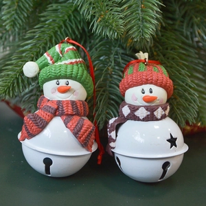 Set of 2 Christmas snowman bell ornaments hanging on a festive green pine tree