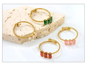Close-up of adjustable gold rope rings with colorful rectangular zircon stones on stone