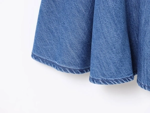 Vista macro dell'orlo di un abito in denim blu con cuciture e trama del tessuto twill