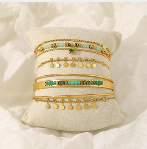 Detail of luxury stackable gold bracelets with turquoise beads and evil eye charms