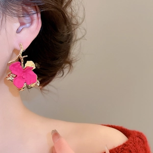 Close-up of model wearing rose red floral earrings with golden curved hooks