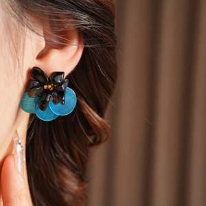 Close-up of vintage shell and tiger eye petal earrings on model with high gloss finish