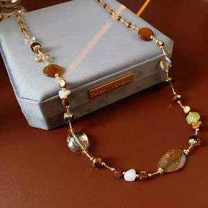 Close-up of irregular amber and white beads on a vintage layered necklace with gold accents
