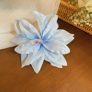 Close-up of a light blue fabric lily hair clip with silk petals and pink stamens