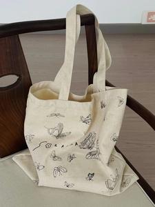 Detailed view of the butterfly print on a cream canvas tote bag over a wooden chair