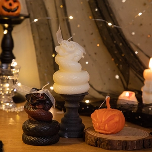 Halloween skull and pumpkin candles with roses and snakes in a festive spooky setting