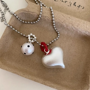 Macro shot of silver beaded chain with heart pendant and polka dot bead detail