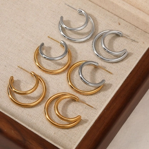 Double-layered C-shaped hoop earrings in gold and silver finish on a linen tray