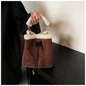 Detail of suede bucket bag with faux fur trim, drawstring closure and gold hardware