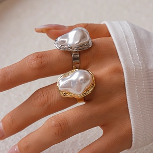 Close-up of gold and silver baroque pearl rings with irregular metal wrap details