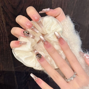 Vue détaillée d'ongles trapèze longs avec dégradé œil-de-chat rose et nœuds en strass 3D