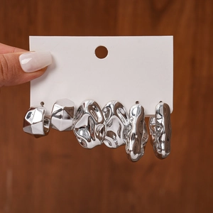 Detailed view of silver irregular geometric fluid stud earrings set on a white display card