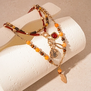 Detail of vintage bohemian layered necklace with butterfly coin and red gemstone charms