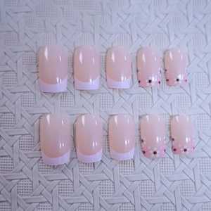 Pink French almond press-on nails with floral patterns and polka dots on a white base