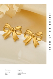 Detailed view of elegant 18K gold plated bow stud earrings on a white ceramic surface