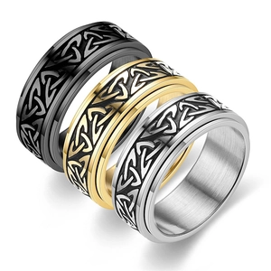 Detailed view of three Celtic knot spinning rings in black, gold and silver steel finish