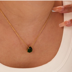 Close-up of 18k gold plated necklace with teardrop emerald zircon on a model