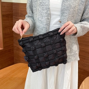 Close-up of black puffy quilted vanity bag with soft canvas bubble texture and zipper