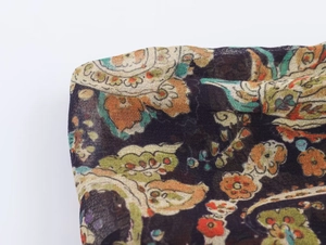 Détail du tissu bohème à motif paisley semi-transparent en orange et vert
