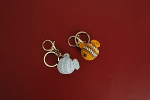 Detail of handmade crochet clownfish and bee keychains with premium gold-tone metal rings