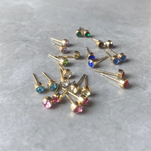 Macro detail of multicolored 12-month crystal stud earrings in gold-plated settings