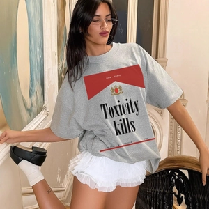 Λεπτομέρεια γκρι βαμβακερού T-shirt με γραφικό Toxicity Kills και γραμμή με πεσμένους ώμους