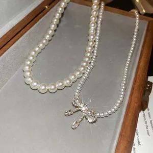 Elegant double-layered pearl necklace with zircon bow pendant set on grey velvet display