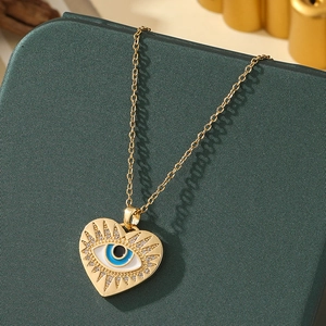 Close-up of golden heart pendant featuring a blue evil eye design and small cubic zirconia