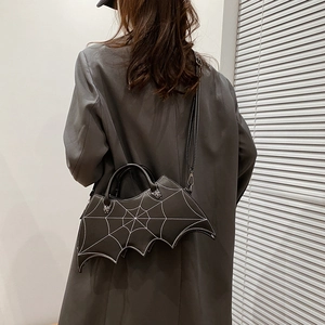 Close-up of black PU leather bat-shaped bag with embroidery on a model’s back