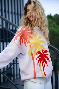 Detail of white knit sweater with vibrant orange palm tree jacquard and ribbed crew neck