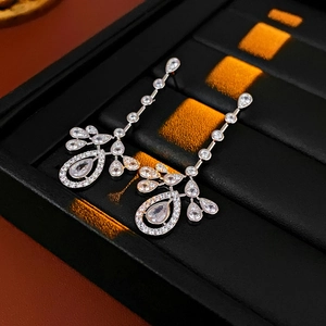 Detailed view of silver drop earrings with zircons on a professional black tray