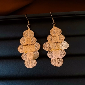 Close-up of golden layered leaf drop earrings with intricate hollow mesh texture detail