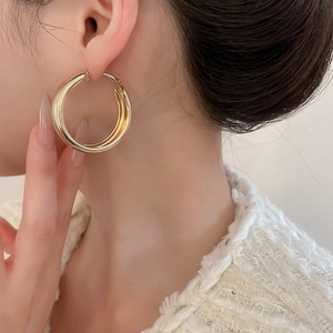 Close-up of chunky gold hoop earring with mirror finish on a female model