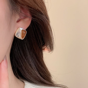 Close-up of geometric square earrings with marble pattern and amber resin on ear